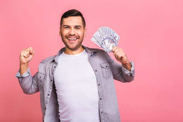 Foto feliz ganador joven rico en casual sosteniendo dinero billetes de un dólar con sorpresa