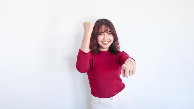 Feliz y ganadora hermosa chica asiática con camisa roja de fondo blanco