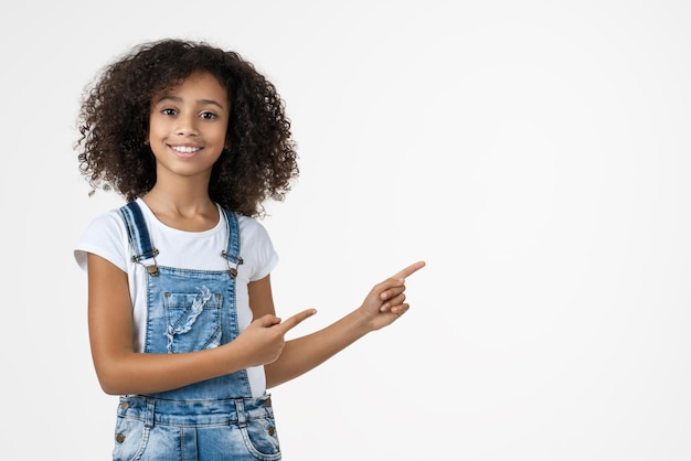 Foto feliz garota afro-americana apontando os dedos para o lado no espaço da cópia isolado sobre o fundo branco