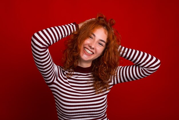 Foto feliz garota ruiva com sorriso bonito, posando sobre fundo vermelho