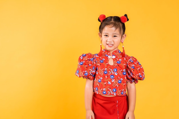 Feliz garotinha chinesa asiática sorri vestindo cheongsam vermelho