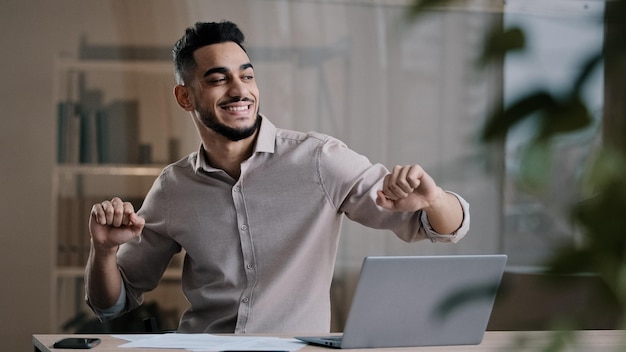 feliz gracioso hombre de negocios árabe hispano joven hombre sonriente hombre activo bailando en la oficina de casa