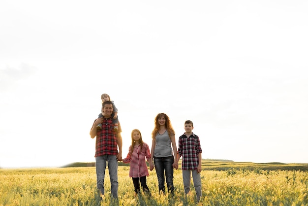 Feliz gran familia mamá con papá e hijos en la naturaleza en el fondo del cielo al atardecer Padres e hijos caminan juntos Concepto de relaciones familiares felices Infancia y crianza de los hijos