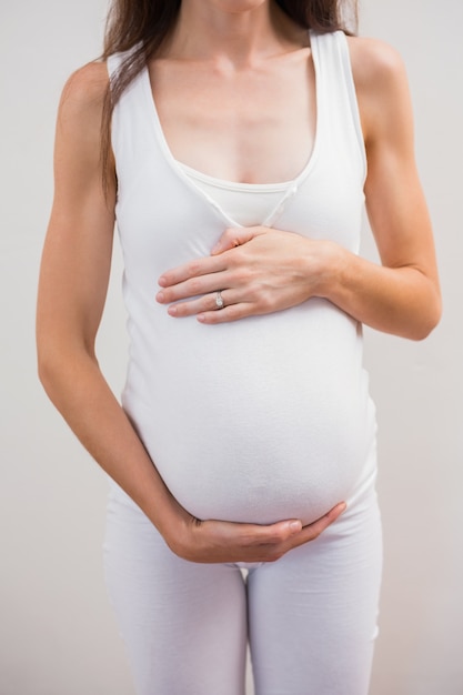 Feliz gravidez em pé toca sua barriga