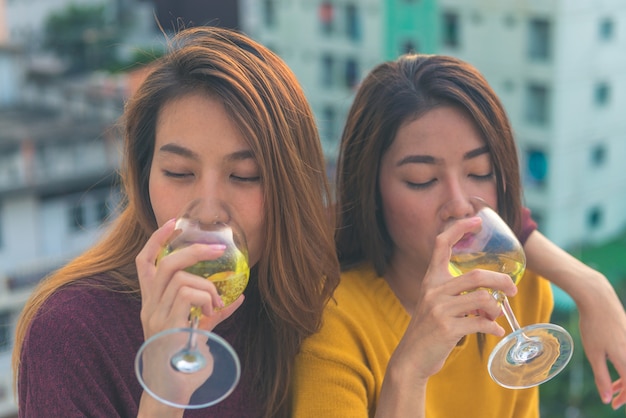 Feliz grupo de amigas asiáticas disfruta riendo y alegre copa de vino espumoso en la fiesta en la azotea