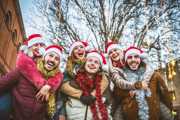 Feliz grupo de amigos con sombrero de Papá Noel celebrando juntos la noche de Navidad