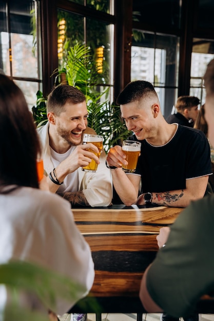 Feliz grupo de amigos bebendo e tilintando com cerveja e coquetéis no bar restaurante da cervejaria Conceito de estilo de vida de bebidas com rapazes e garotas se divertindo juntos