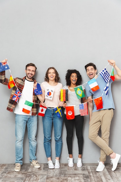 Foto feliz grupo de amigos segurando muitas bandeiras internacionais.