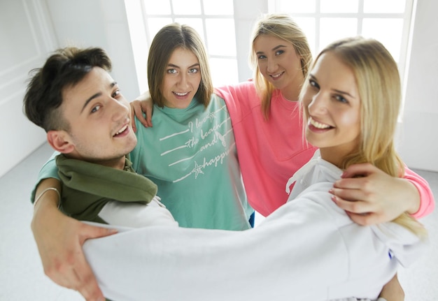 Feliz grupo de amigos sorridentes de jovens em pé e abraçando juntos