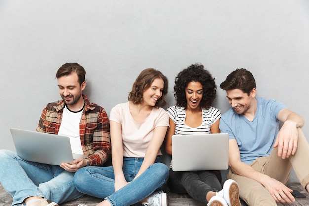 Foto feliz grupo de amigos usando laptops.