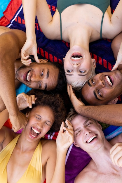 Feliz grupo diversificado de amigos deitados em toalhas e rindo no jardim. Estilo de vida, amizade, festa e verão.