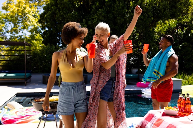 Foto feliz grupo diversificado de amigos fazendo festa na piscina, churrasco e dançando no jardim. estilo de vida, amizade, festa e verão.