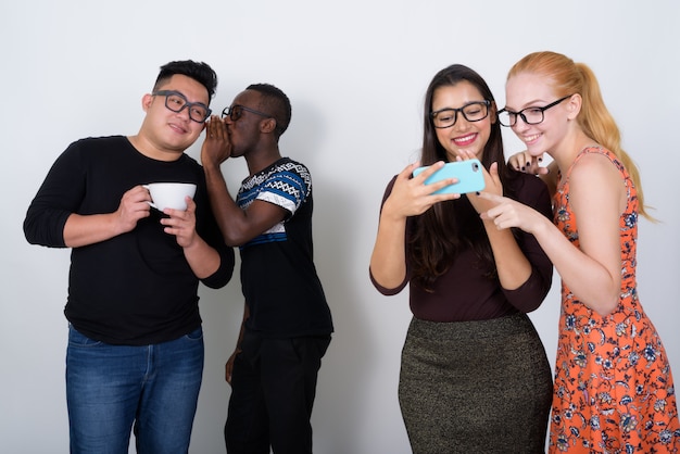 Feliz grupo diversificado de amigos multiétnicos sorrindo enquanto usam telefones