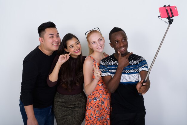 Feliz grupo diverso de amigos multiétnicos sonriendo mientras toma un selfie