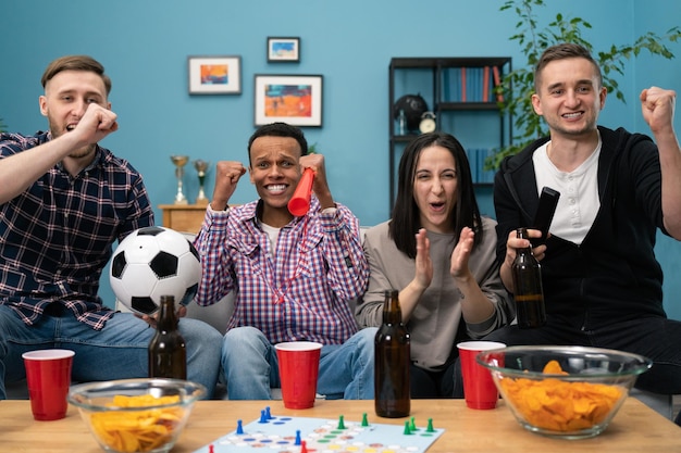 Feliz grupo diverso de estudiantes aficionados al deporte levantando los brazos emocionados celebrando la observación de goles