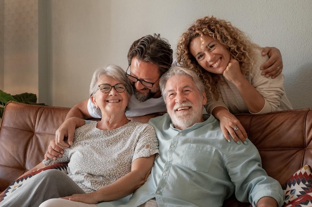 Feliz grupo familiar multigeneracional sentado en un sofá en casa pasando tiempo juntos Cuatro personas