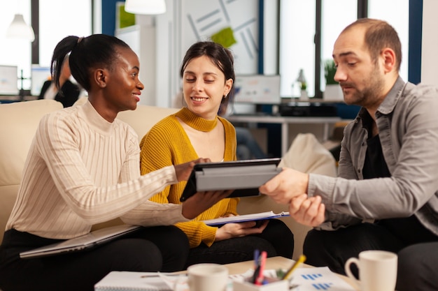 Feliz grupo multiétnico de gente de negocios mirando ideas de información de tableta en la oficina de la empresa de inicio corporativo moderno