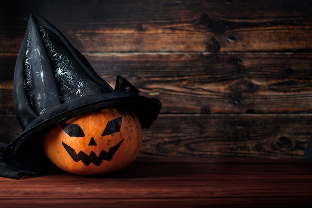 ¡Feliz Halloween! Calabaza con un sombrero de bruja sobre un fondo de madera. Lugar para el texto.