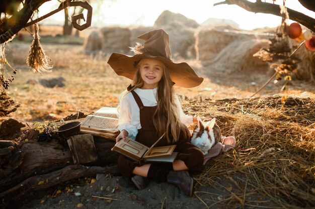 Feliz Halloween. Una linda chica con un disfraz de bruja está en la guarida de la bruja. Linda brujita alegre prepara una poción mágica. Víspera de Todos los Santos.