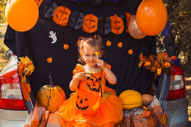 Feliz halloween linda niña con calabazas en el maletero del coche