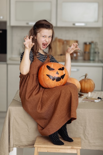 Foto feliz halloween. niña linda en traje de bruja con calabaza tallada. familia feliz preparándose para halloween.