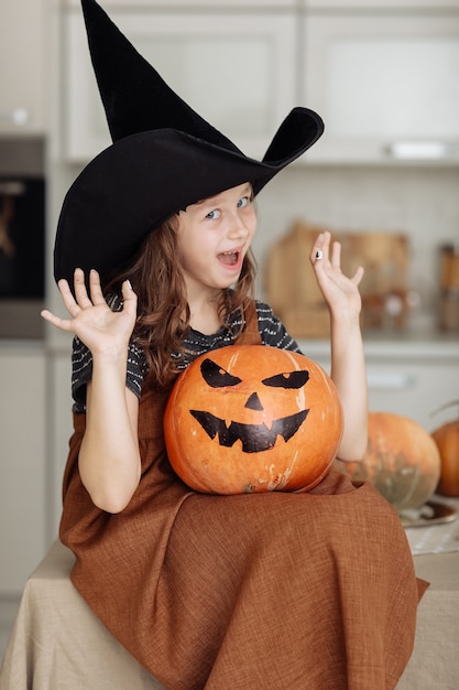 Feliz Halloween. Niña linda en traje de bruja con calabaza tallada.