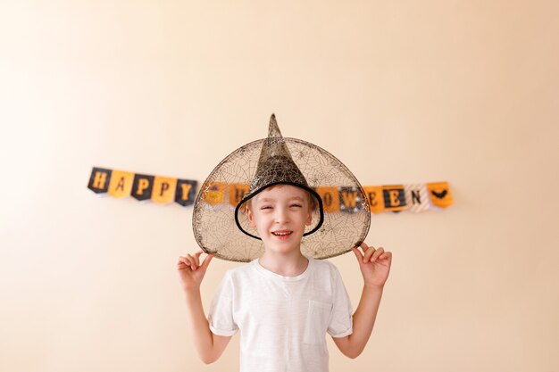 ¡Feliz Halloween! Pequeño mago lindo con una calabaza sobre fondo beige.