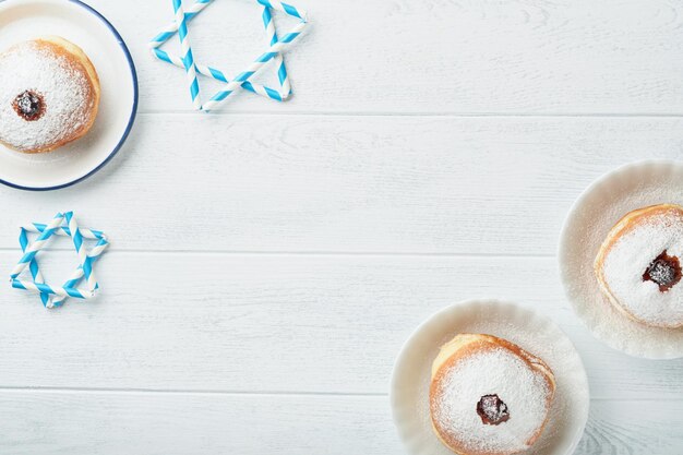Feliz Hanukkah Hanukkah dulces donas cajas de regalo velas blancas y monedas de chocolate sobre fondo blanco de madera Imagen y concepto de vacaciones judías Hanukkah Vista superior
