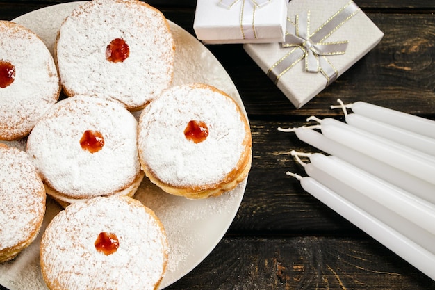 Feliz Hanukkah Sobremesa tradicional Sufganiyot no fundo escuro de madeira Donuts velas e presentes Comemorando o feriado judaico