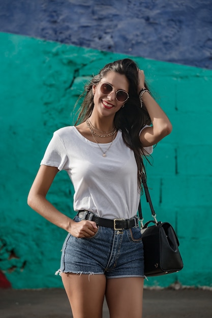 Foto feliz hembra joven de pie al aire libre y sonriente