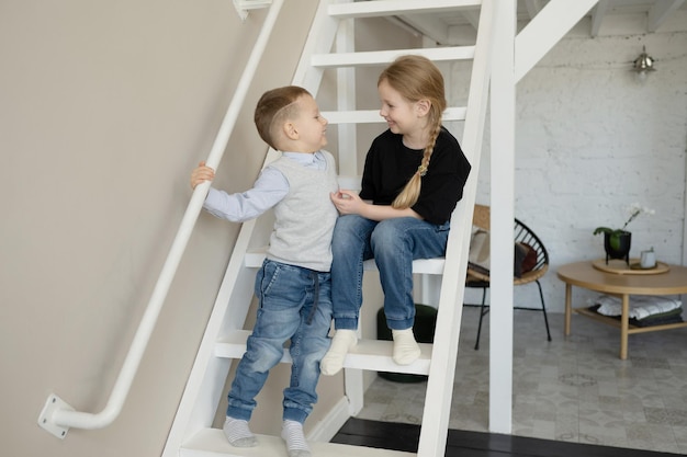 Feliz hermano y hermana en edad preescolar, riendo y abrazándose, en casa.