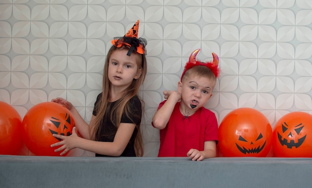 Feliz hermano y hermana en una fiesta de Halloween. El concepto de niños listos para una fiesta. vestidos con disfraces, máscaras y sombreros de miedo, con gestos aterradores. Enfoque selectivo.