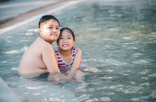 Feliz hermano y hermana jugando en la piscina