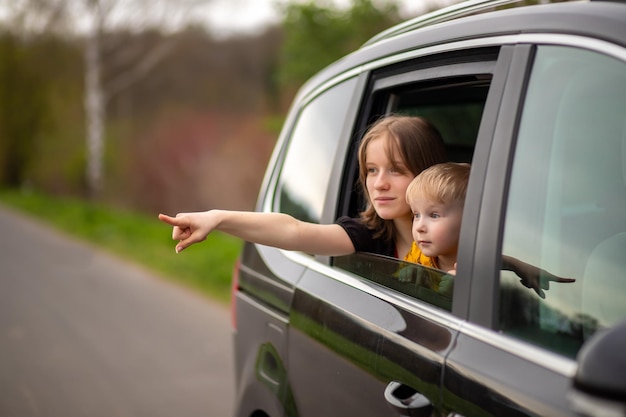 Feliz hermano y hermana mirando por la ventana del auto