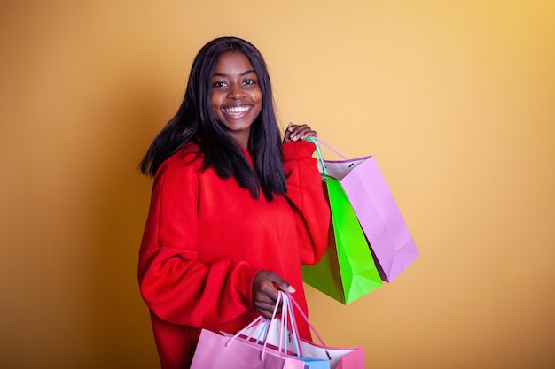 Feliz y hermosa chica afroamericana con una capucha roja con bolsas coloridas