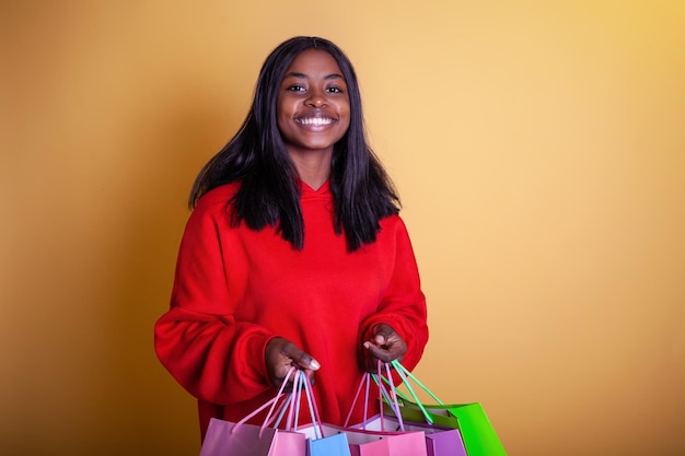 Feliz y hermosa chica afroamericana con una capucha roja con bolsas coloridas