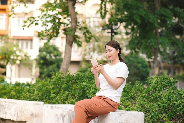 Feliz hermosa chica con teléfono inteligente al aire libre