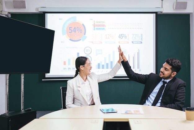 Una feliz, hermosa e inteligente mujer de negocios asiática celebra chocando los cinco y etiquetándose de la mano con su colega para el trabajo en equipo de unidad y proyectos exitosos en la sala de reuniones de la oficina