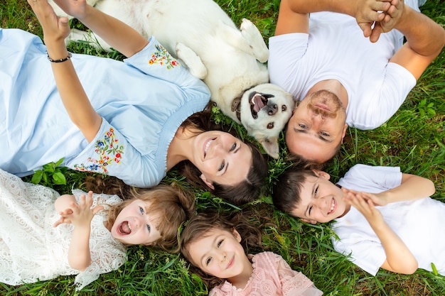 Feliz hermosa gran familia juntos madre, padre, hijos y perro acostado en la vista superior de la hierba