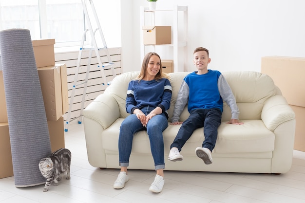 Feliz hermosa joven madre soltera y un hijo positivo están sentados en el sofá junto a su