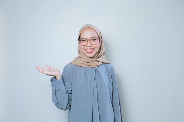 Feliz hermosa joven mujer de negocios musulmana asiática con gafas apuntando a un área en blanco