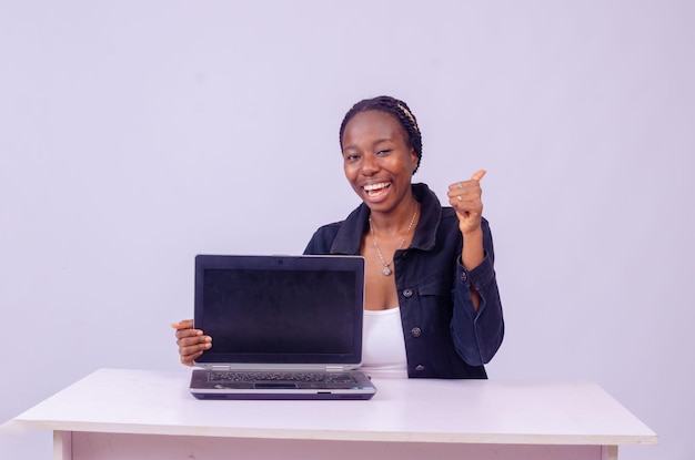 Feliz hermosa joven negra mostrando la pantalla de su computadora portátil