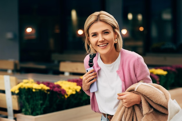 Feliz hermosa joven rubia con camiseta blanca y chaqueta rosa sonriendo y caminando por la calle de la ciudad Bonita estudiante posando en la calle