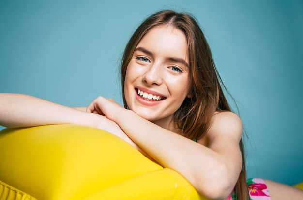 Feliz hermosa joven rubia de fondo azul en traje de baño o bikini y sonriendo mientras posa. Verano y vacaciones