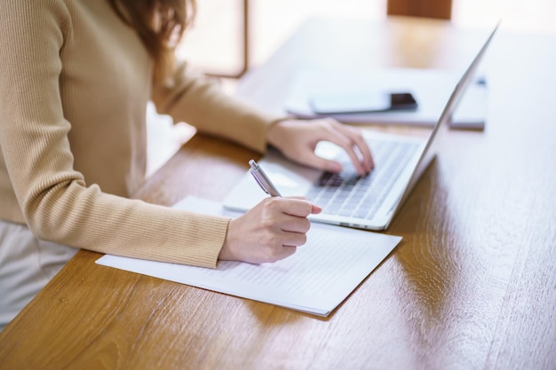 Feliz hermosa mujer asiática Mujer de negocios que trabaja desde casa con una computadora portátil Concepto de espacio de trabajo en el hogar financiero