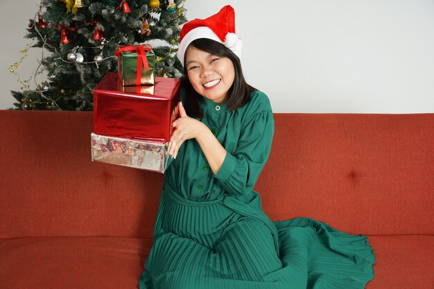 Feliz hermosa mujer asiática con vestido verde y gorro de Papá Noel celebración de Navidad con regalo