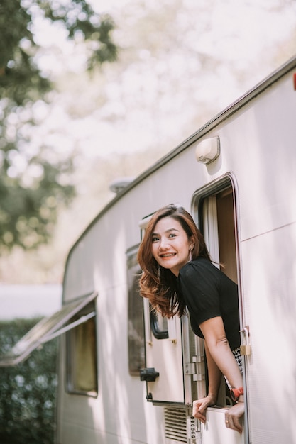 Feliz hermosa mujer bastante asiática por la ventana de la autocaravana