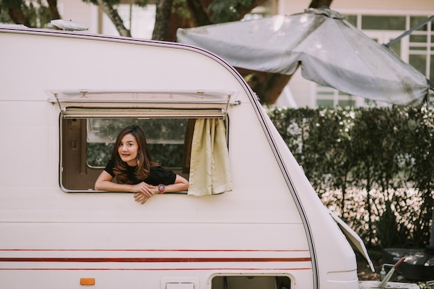 Feliz hermosa mujer bastante asiática por la ventana de la autocaravana