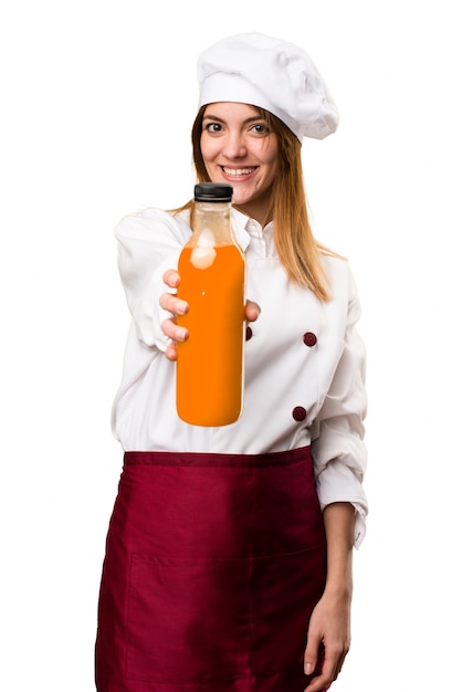 Feliz hermosa mujer chef sosteniendo un jugo de naranja