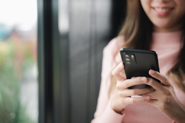 Feliz hermosa mujer escribiendo mensajes de texto en un dispositivo de teléfono inteligente y disfrute de un estilo de vida